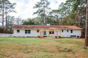 The rear back exterior of a newly painted and renovated white brick ranch style house with a large...