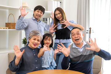 Obraz premium Big family of love, including a grandfather and granddaughter, father and mother are posing for a picture. They are all smiling and waving at the camera. Scene is happy and joyful