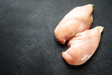 Uncooked chicken fillet at black table. Top view with copy space.