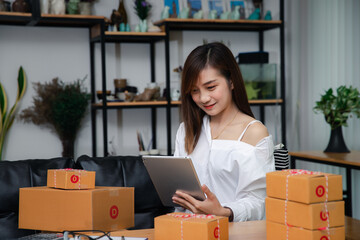 Successful entrepreneur business woman using laptop to check and prepare parcel box of product for...