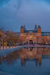Deurstickers Amsterdam, Netherlands March 25 2022: Amsterdam in a cold night during spring season. Famous national Rijks museum general view reflecting in tha water at dusk © badescu