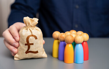 A businessman holds a british pound sterling money bag near a group of people figurines....