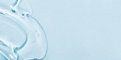 The smear of a transparent gel on a blue background. The texture of the skin or hair care product.