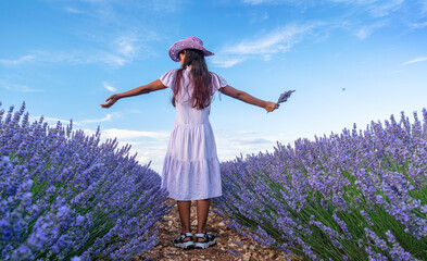 Young girl in the lavender field and cloudy sky at the background. Brihuega, Spain. - 755782453