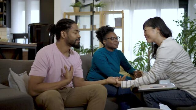 Upset couple sitting on couch at counselor's office, ignoring each other, having problems in relationship.