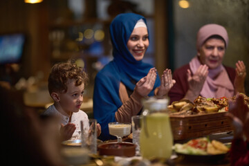 In a modern restaurant setting, a European Islamic family comes together for iftar during Ramadan, engaging in prayer before the meal, uniting tradition and contemporary practices in a celebration of