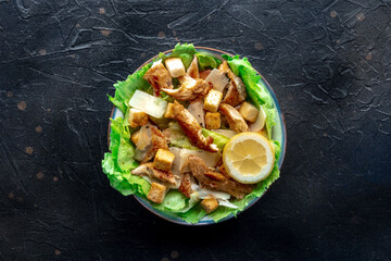 Caesar salad with chicken breast, lettuce, croutons, and a lemon, overhead flat lay shot on a slate background - 755792062