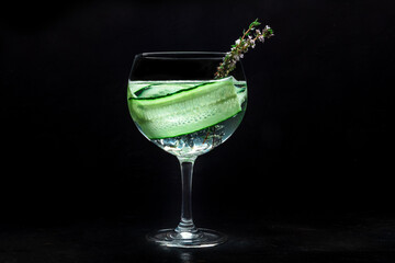 Fancy fresh cocktail. Gin and tonic drink with ice at a party, on a black background. Alcohol with cucumber and thyme - 755793025