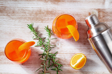 Orange cocktails with rosemary and a shaker, overhead flat lay shot on a wooden background - 755793498