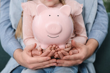 Family budget. Little girl and her parents with piggy bank, closeup