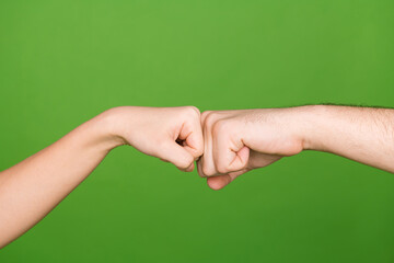 Photo of two female male arms touching fists fighting showing confrontation isolated green color...
