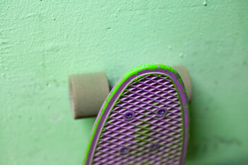The longboard stands against the wall. Big wheels on the board. Sports equipment for skating.