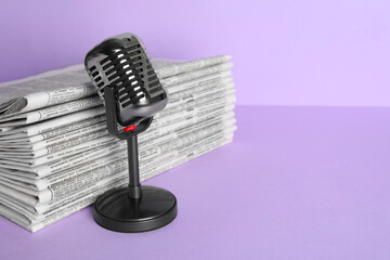 Fototapeta na wymiar Newspapers and vintage microphone on light violet background, space for text. Journalist's work
