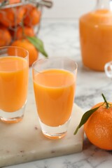 Delicious tangerine liqueur and fresh fruits on white marble table, closeup