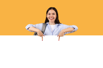Happy lady student pointing down at blank banner
