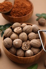 Nutmeg powder and seeds on light brown background