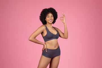 Happy black woman in underwear attire showing OK sign - obrazy, fototapety, plakaty