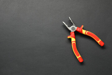 Combination pliers on black background, top view. Space for text