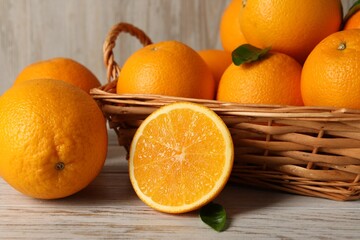 Many whole and cut oranges on light wooden table, closeup
