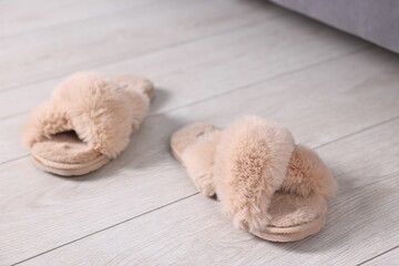 Beige soft slippers on light wooden floor at home