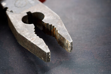 Worn pliers on a black workbench.