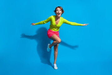 Fototapeta na wymiar Full length body photo of charming lady dressed green cardigan with pink mini skirt flying forward isolated on blue color background