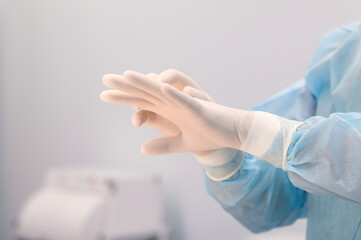 Nurse or doctor puts on white nitrile surgical gloves