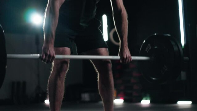 Athlete sportsman weightlifting doing a deadlift with barbell bar in a dark modern gym
