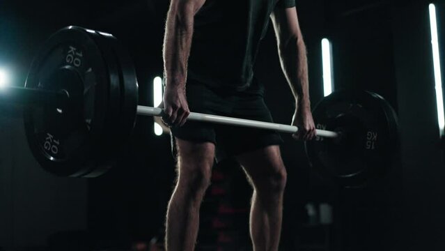 Close up shot - Unrecognisable man doing a deadlift, weight training in the gym with a dark background and mood lightening