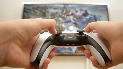 Close-up of a professional gamer's hands operating a PS controller. Home game console, modern...