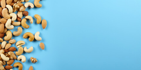Top view dried almonds, peanuts, walnuts and cashew nuts on a blue background. Blank space for product placement or advertising text.