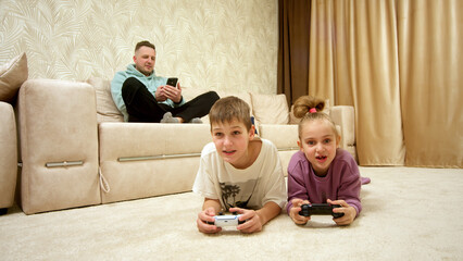 Happy father with children playing video console at home. Concept of family vacation, victory and...