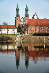 Historic buildings and towers of the gothic cathedral on the Warta River in the city of Poznan, - obrazy, fototapety, plakaty