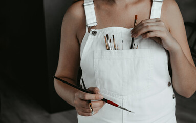 portrait of a  woman artist in a white sundress with a palette for paints and brushes for painting