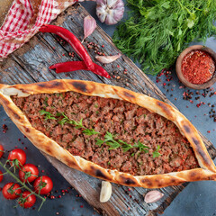 Top view of Turkish pide with minced meat, 
green peppers  on wooden tray. with ingredients around  Turkish name; Kiymali Pide. Traditional Turkish cuisine. Turkish pizza Pita with meat