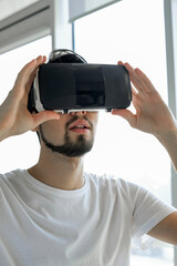 Young man vigorously plays virtual reality video game wearing VR glasses at home