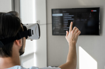 Young man vigorously plays virtual reality video game with control panel