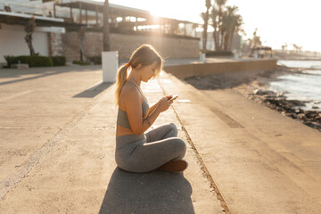 A woman sitting near the beach with a phone and relaxing