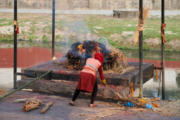 Staff employee of Pashupatinath Temple complex overseeing for funeral pyre for cremation ceremony,...