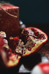 Ripe pomegranate fruit. Slices of pomegranate lying on a wooden table near wrapped box. Closeup