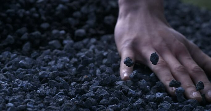 Super slow motion macro of labour worker touches gravel stones on ground with his hands during quality control and sorting process at concrete plant industrial factory at 1000 fps.