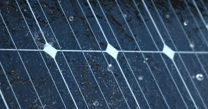 Super slow motion macro of transparent clear crystal rainwater drops falling on high efficiency solar energy panels at photovoltaic power plants farm. Renewable, sustainable alternative green energy.