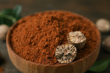 Nutmeg powder and halves of seed in bowl on table, closeup
