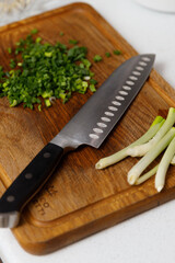 Kitchen knife and board with fresh green onions. Cooking lunch.
