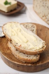 Slices of tasty bread with butter on white wooden table, closeup. Space for text