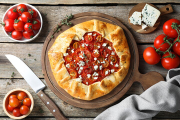 Flat lay composition of tasty galette with tomato, thyme and cheese (Caprese galette) on wooden...