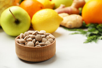 Dietary supplements in wooden bowl and products on white table, closeup. Space for text