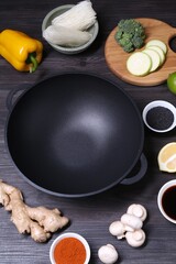 Empty iron wok and ingredients on dark grey wooden table, above view