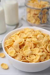 Tasty crispy corn flakes in bowl on white table, closeup. Breakfast cereal