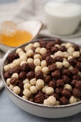 Tasty cereal balls in bowl on grey table, closeup